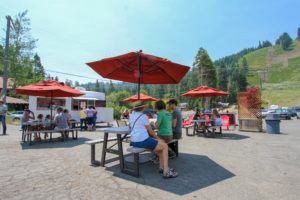 Tahoe Fusion food truck in front of Homewood Mountain Resort. Three people enjoy burritos in the foreground.