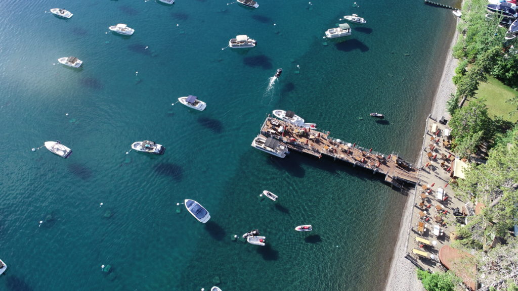 An overhead view shows people enjoying dinner on the West Shore Cafe Pier overlooking Lake Tahoe.