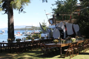 Tables are set for dinner on the West Shore Cafe Lawn. A large rhino sculpture is in the background.