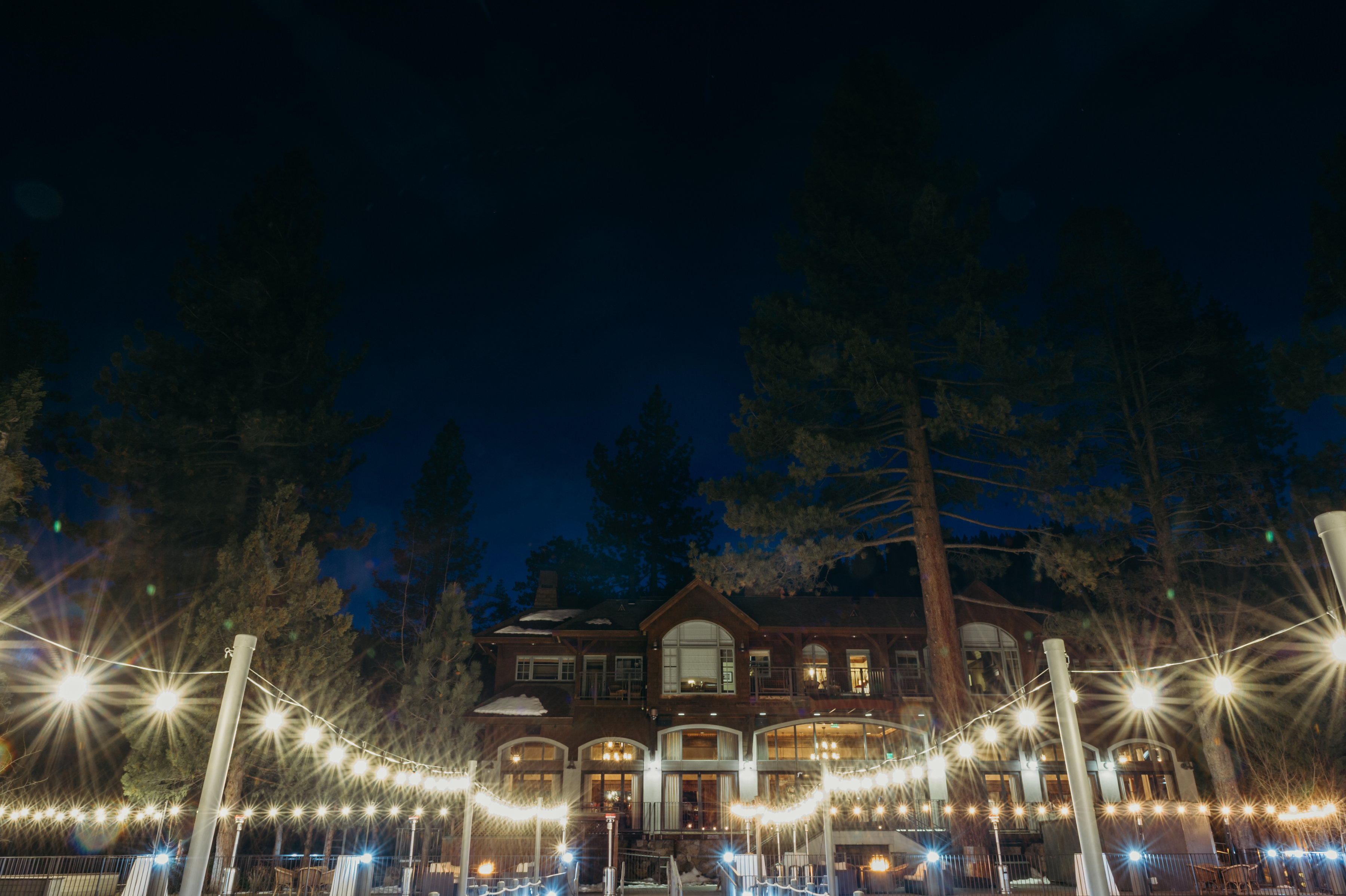 Photo taken from the West Shore Cafe pier looking towards the lodge at dusk. There is market lighting lining the pier.