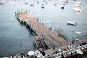 An overhead shot shows the West Shore Cafe Pier. People are seated at long tables on the deck. Lake Tahoe is in the background. Sandra Fazzino Photography