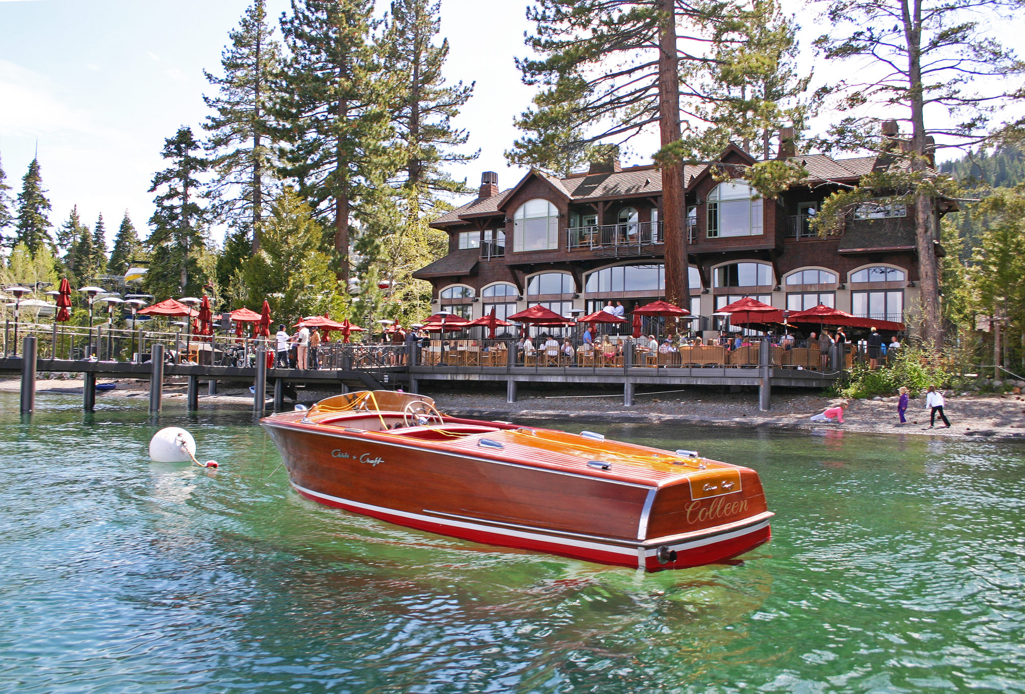 A wooden boat floats on Lake Tahoe in front of the West Shore Cafe.