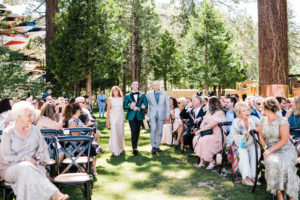 A groom walks down an aisle with his parents on the West Shore Cafe lawn. Custock Photography