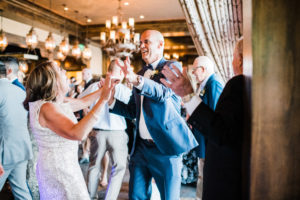 A woman in a silver dress and a man in a blue suit are dancing at West Shore Cafe. Custock Photography
